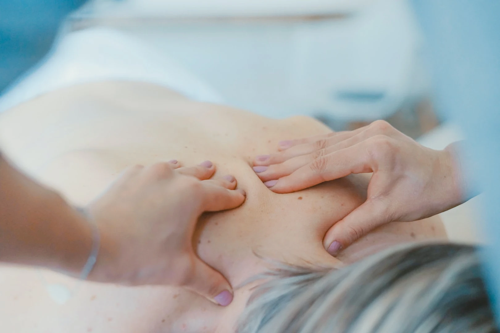 Dłonie osteopatki podczas delikatnej pracy z ciałem pacjentki